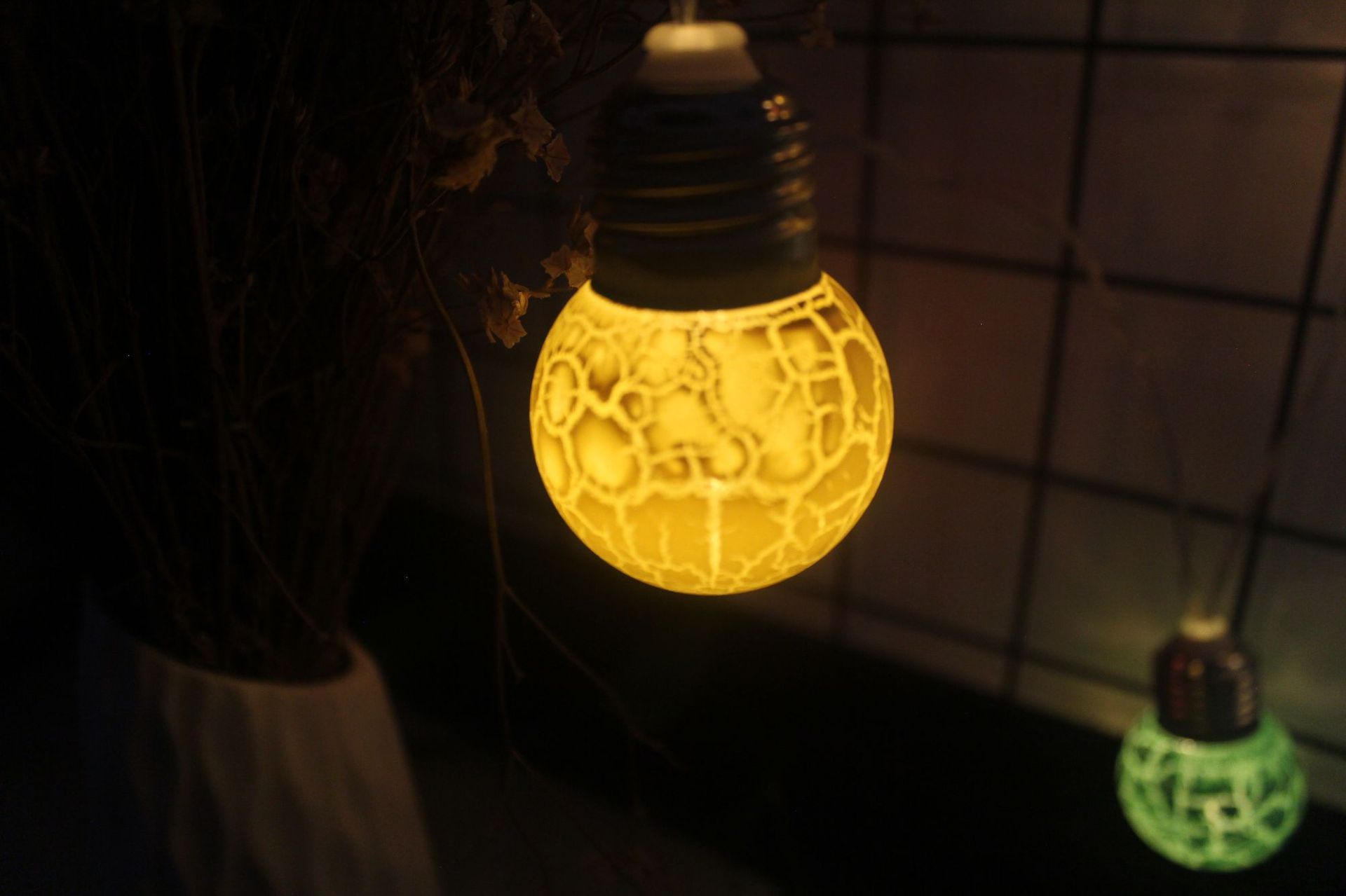 Yellow glowing cracked bulb LED light hanging indoors for festive decoration