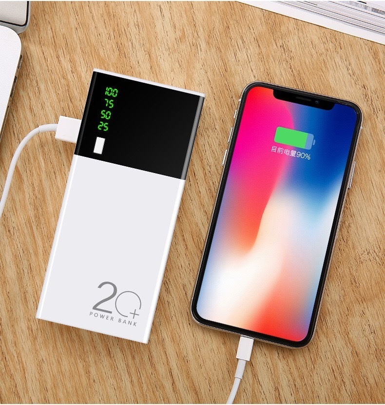 20000mAh power bank charging smartphone on wooden surface.