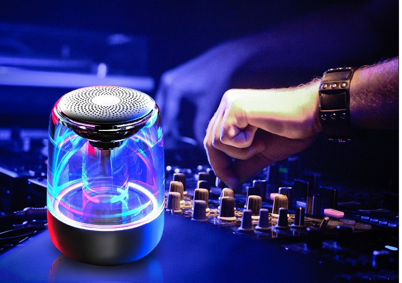 Portable Bluetooth speaker with colorful LED lights and powerful bass in a dark setting.