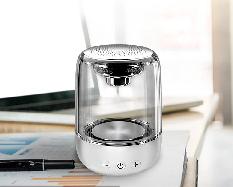 Portable Bluetooth speaker with clear casing, powerful bass, and LED lights, placed on a desk.
